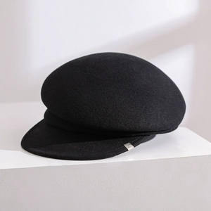 Elegant black wool newsboy cap for women on minimalist white display stand.