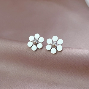 Detailed macro view of six-petal flower titanium steel stud earrings on pink silk