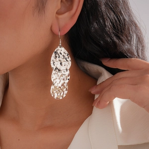 Détail de boucles d'oreilles argentées en forme de goutte avec texture martelée