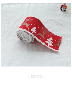 Detail of red Christmas ribbon with golden reindeer and festive white fringe edge