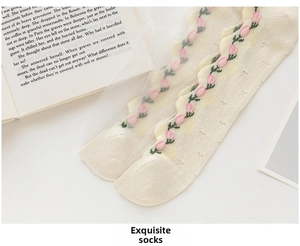 Detail of sheer white socks with pink tulip embroidery and elegant wavy lace cuffs