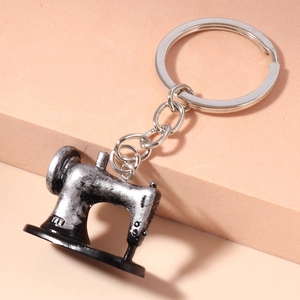 Detailed view of a vintage silver sewing machine keychain on a display stand