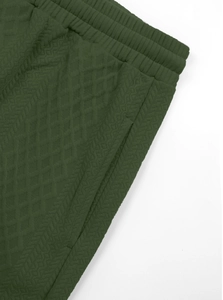 Detail of dark green tracksuit pants showing diamond jacquard texture and elastic waist