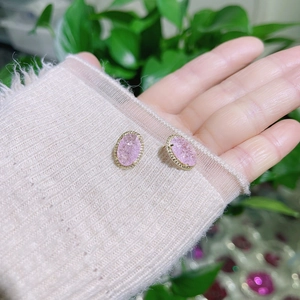 Elegant pink oval crystal stud earrings with gold plating held against soft background