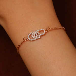 Detail of rose gold paperclip bracelet with zircon stones on a model's wrist