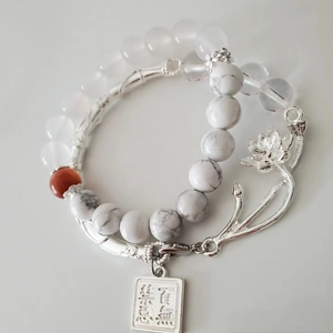Detail of white turquoise beads with metal lotus charms and engraved prayer tags