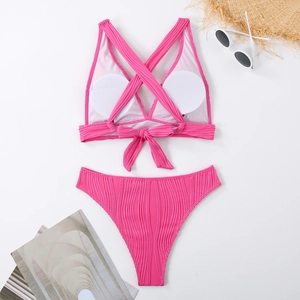 Flachbild von rosa geripptem Bikini-Set mit Strohhut und Sonnenbrille auf weißem Grund