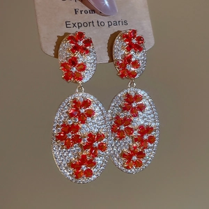 Close-up of vintage flower oval stud earrings with red crystals and white zircons