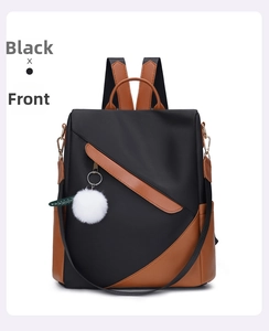 Front view of black waterproof nylon backpack with brown leather trim and fuzzy white pompom