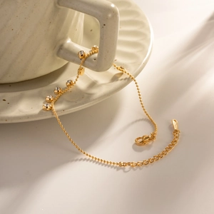 Elegant gold titanium steel bracelet with sparkling crystals on a ceramic surface