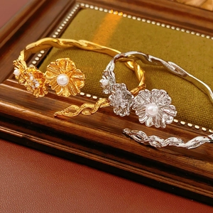 Detailed close-up of vintage flower bangles with pearls and crystals on artistic wood background