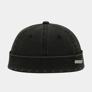 Détail des bords usés et de la plaque métallique sur le bonnet docker noir vintage