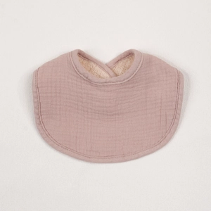 Detailed texture of cotton muslin bib with warm sherpa fleece lining in soft mauve