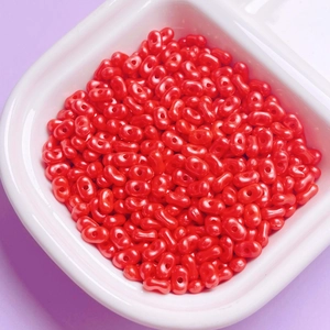 Macro shot of red peanut-shaped acrylic beads with pearl luster for DIY jewelry making