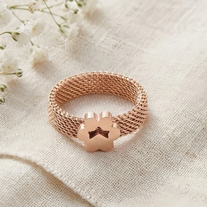 Macro view of rose gold mesh weave ring with a polished paw print charm on linen