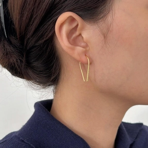 Close-up of minimalist gold V-shaped geometric hoop earrings worn by a model