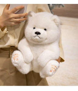 Close-up of fluffy white teddy bear with pink paw embroidery and soft plush texture