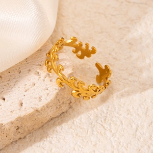 Macro shot of gold leaf vine open ring placed on beige stone with white silk background