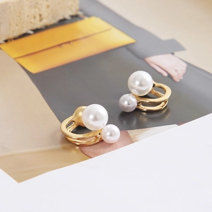 Close-up of elegant double pearl earrings with gold hollow base on a magazine