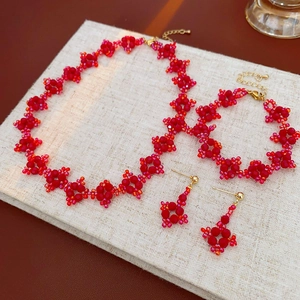 Detailed set of jewelry with red beaded flower necklaces, bracelets, and earrings