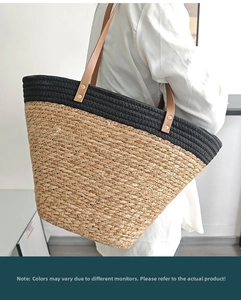 Detail of a large two-tone woven straw tote bag with brown leather straps shown on a model