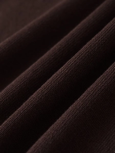 Macro shot of dark coffee knitted polo shirt fabric showing dense woven texture and soft feel