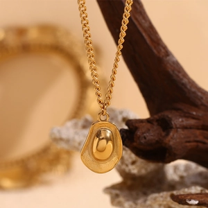 Macro detail of 18K gold plated stainless steel oval pendant on a refined necklace