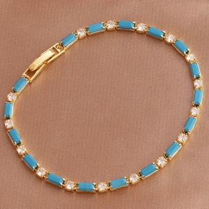 Detailed view of golden bracelet with blue rectangular gems on brown silk background