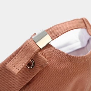 Detail of adjustable metal buckle and strap on back of brick red cotton sailor cap