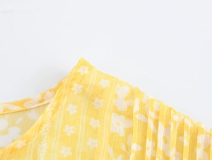 Detailed close-up of yellow floral fabric with white daisy patterns and fine stitching