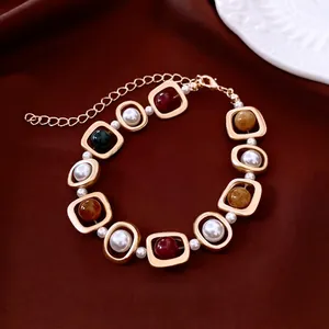 Bracelet vintage doré géométrique avec perles et billes colorées sur velours rouge