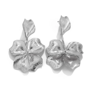 Detail of silver flower earrings with brushed metallic texture and organic petal design
