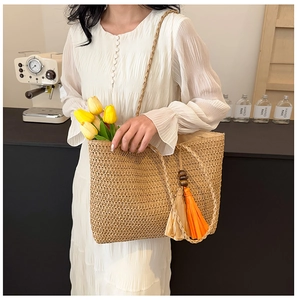 Straw tote bag detail with braided straps, tassels and wooden beads for beach holiday