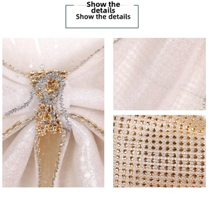 Macro detail of white satin Christmas bow with sparkling gold rhinestones and sequins
