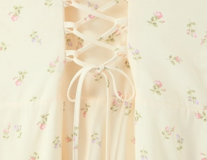Detail of floral halter dress featuring corset lacing and delicate pink flower patterns