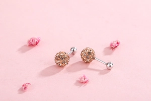 Macro view of crystal paved ball earrings with rose gold finish and silver screw back