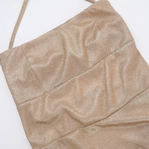 Close-up detail of golden glitter fabric texture on a sexy backless halter dress for women