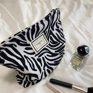 Detailed view of the zebra print canvas cosmetic bag with zipper and logo patch