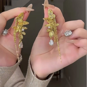 Detail of gold tassel earrings with butterfly leaf motifs and inlaid gemstones