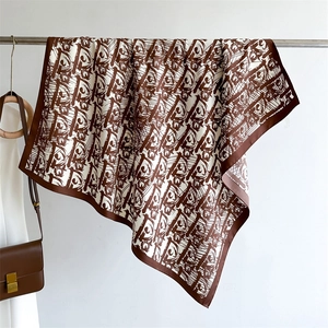 Close-up detail of luxury silk scarf showing brown and white abstract letter patterns