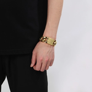 Close-up of a 24mm gold plated Cuban chain bracelet worn by a model in black casual wear