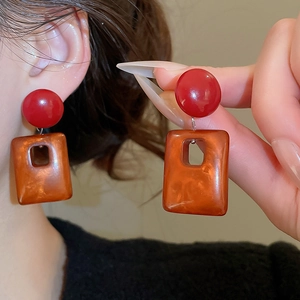Detailed close-up of retro square acrylic pendant earrings with amber resin texture