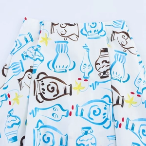 High-waisted white midi skirt featuring blue vase prints and yellow floral patterns