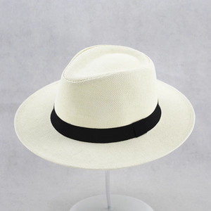 Detail of a beige wide-brimmed straw fedora with a black ribbon band and fine weave texture