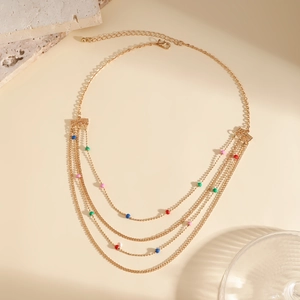 Detail of layered gold chain necklace featuring vibrant colorful beads and a lobster clasp