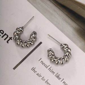 Detailed view of silver twisted croissant hoop earrings on minimalist white card