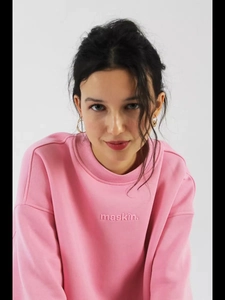 Detailed close-up of pink crewneck sweatshirt with maskin. 3D textured embroidery