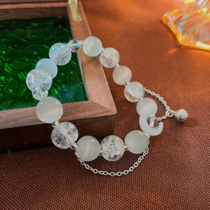 Detail of beaded moon bracelet with opal stones and small bell on vintage wooden box