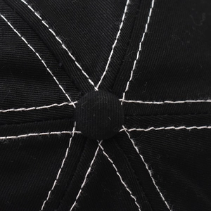 Close-up of black cotton baseball cap top showing white stitching and fabric button detail