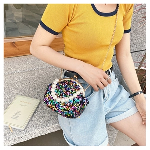 Model showing a colorful sequin shell bag with pearl handle and metal chain strap